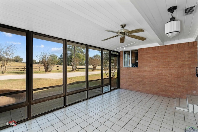 unfurnished sunroom featuring a rural view, a wealth of natural light, and ceiling fan