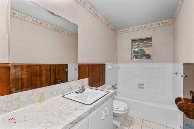 bathroom featuring tile patterned floors, a bathtub, vanity, toilet, and wood walls