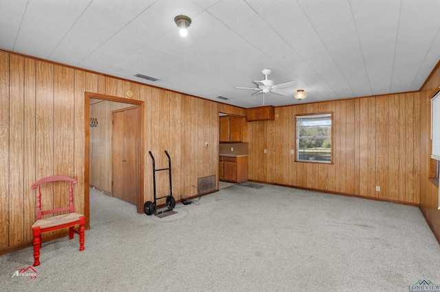 carpeted living room featuring ceiling fan and wooden walls