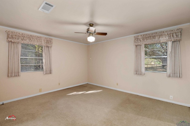 empty room featuring ceiling fan, plenty of natural light, carpet floors, and crown molding