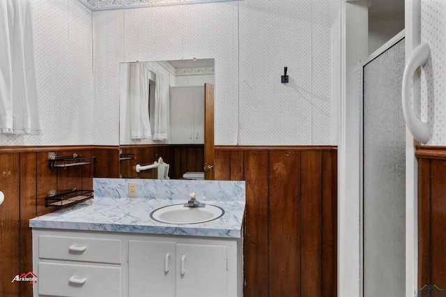 bathroom featuring wood walls, a shower with door, vanity, and toilet