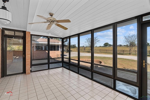 unfurnished sunroom with ceiling fan, a rural view, wood ceiling, and lofted ceiling