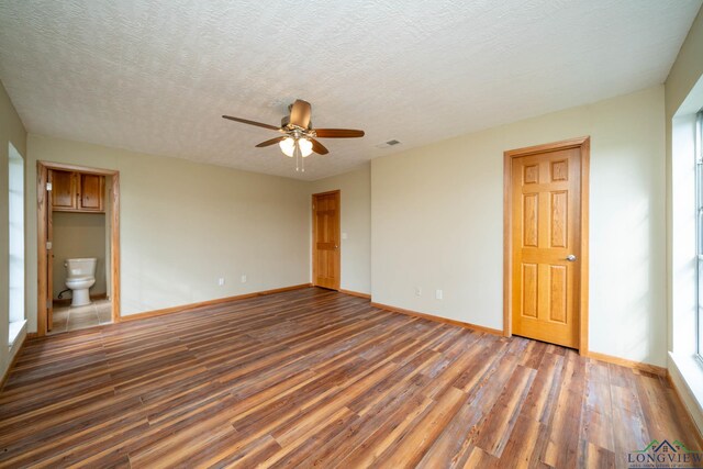 empty room featuring dark hardwood / wood-style floors, ceiling fan, and a textured ceiling