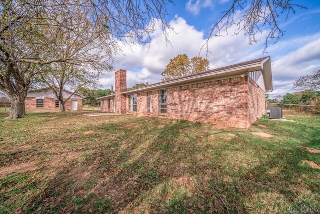 rear view of property featuring cooling unit and a yard