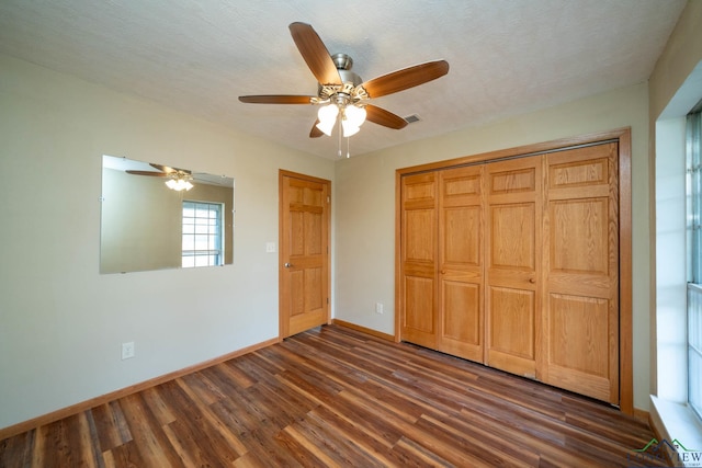 unfurnished bedroom with a textured ceiling, a closet, ceiling fan, and dark hardwood / wood-style floors