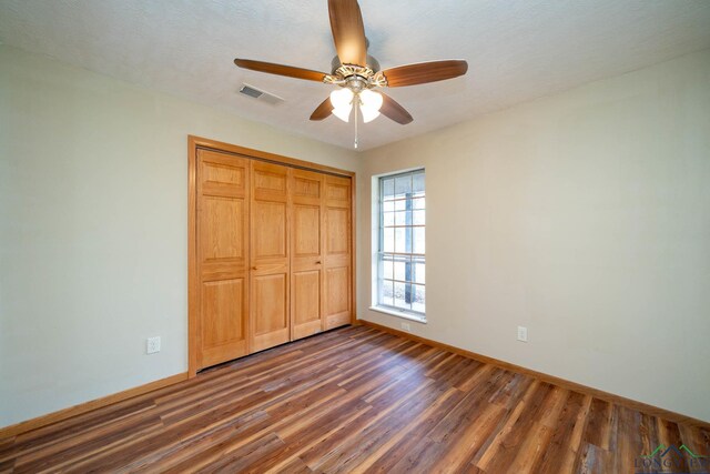 unfurnished bedroom featuring ceiling fan, dark wood-type flooring, and a closet