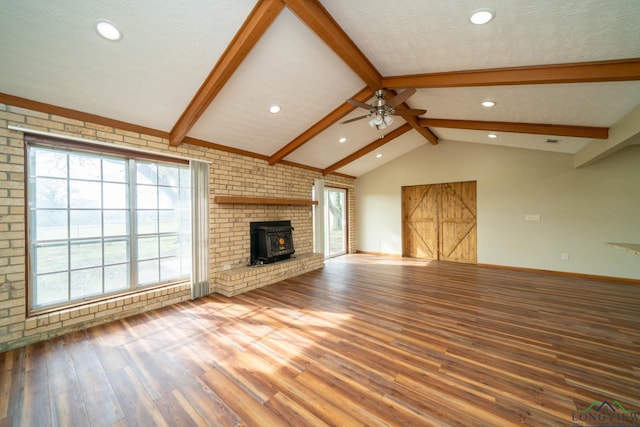 unfurnished living room featuring hardwood / wood-style floors, vaulted ceiling with beams, a wood stove, and ceiling fan