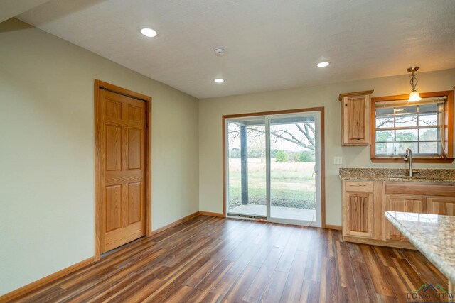 kitchen featuring pendant lighting, light brown cabinets, sink, dark hardwood / wood-style floors, and light stone countertops