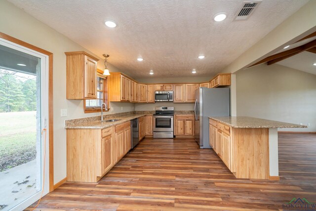 kitchen featuring decorative light fixtures, light stone countertops, sink, and appliances with stainless steel finishes