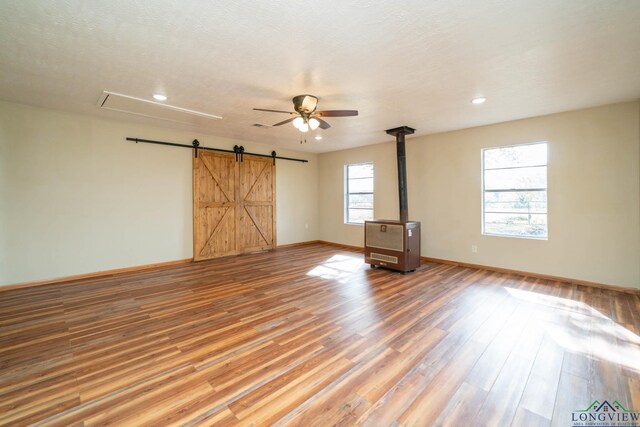 unfurnished room featuring wood-type flooring, a barn door, and ceiling fan