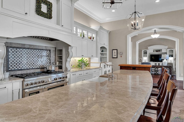 kitchen with range with two ovens, white cabinetry, sink, and tasteful backsplash