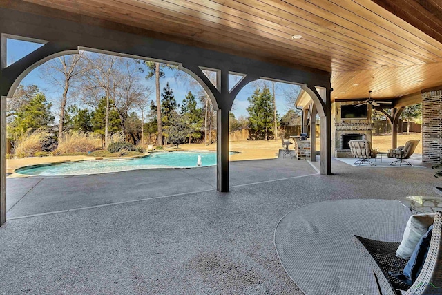 view of pool with exterior fireplace, a patio, and ceiling fan