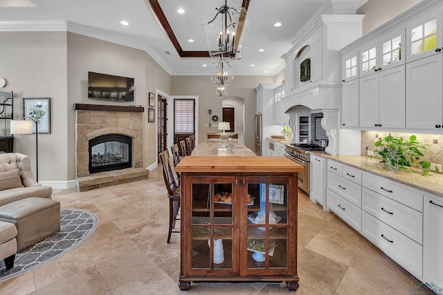 kitchen featuring pendant lighting, a stone fireplace, white cabinets, and appliances with stainless steel finishes