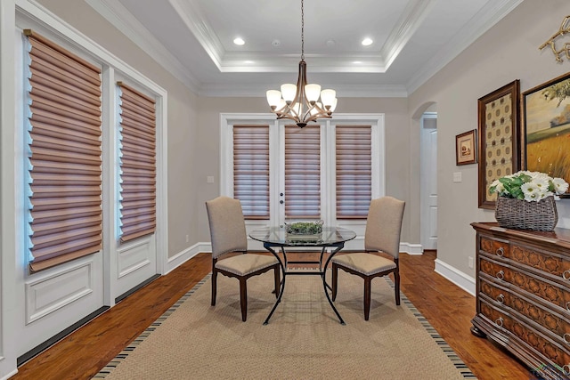 dining space with crown molding, hardwood / wood-style flooring, and a raised ceiling