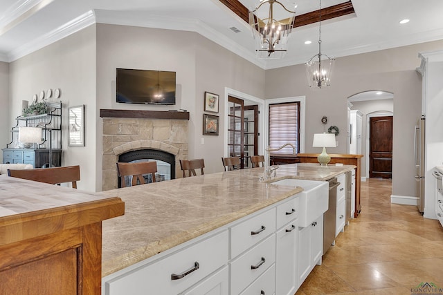 kitchen with pendant lighting, a fireplace, white cabinets, stainless steel dishwasher, and crown molding