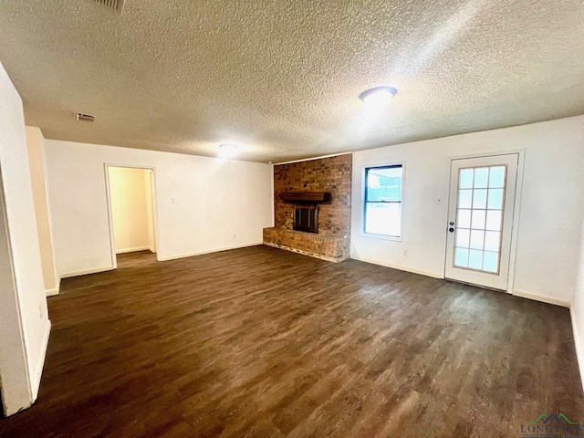 unfurnished living room featuring a textured ceiling, a brick fireplace, and dark wood-type flooring