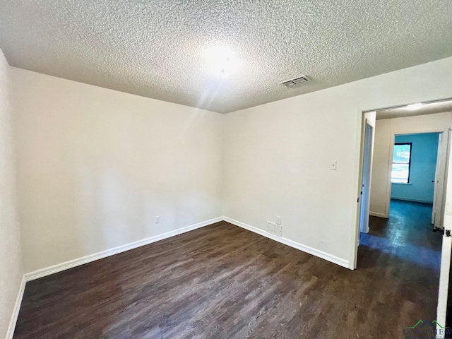 empty room with a textured ceiling and dark hardwood / wood-style floors