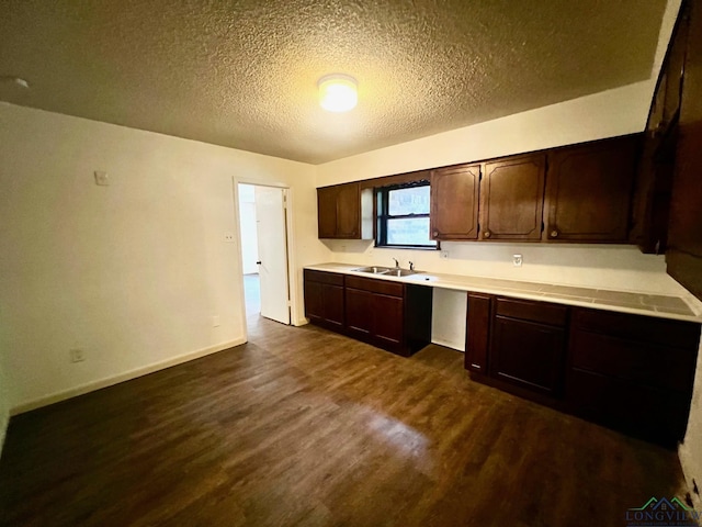 kitchen featuring a textured ceiling, dark brown cabinets, sink, and dark wood-type flooring