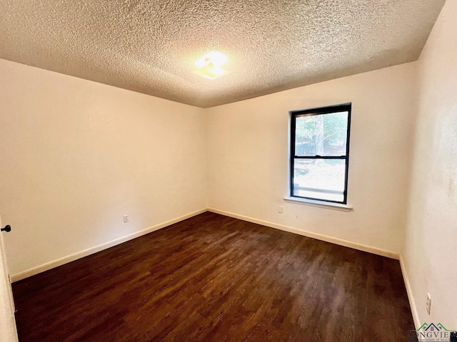 spare room with a textured ceiling and dark wood-type flooring