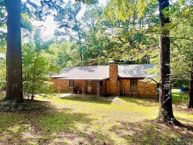 rear view of property featuring a yard and a patio area