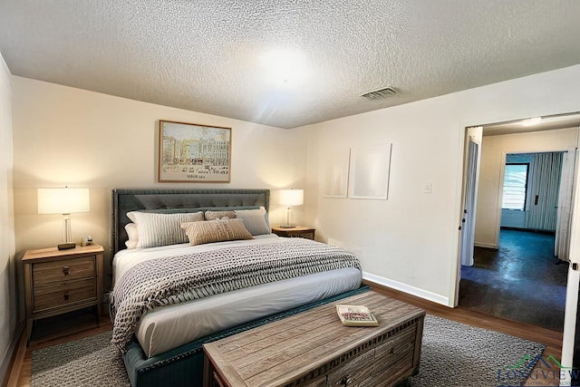 bedroom with a textured ceiling and dark wood-type flooring