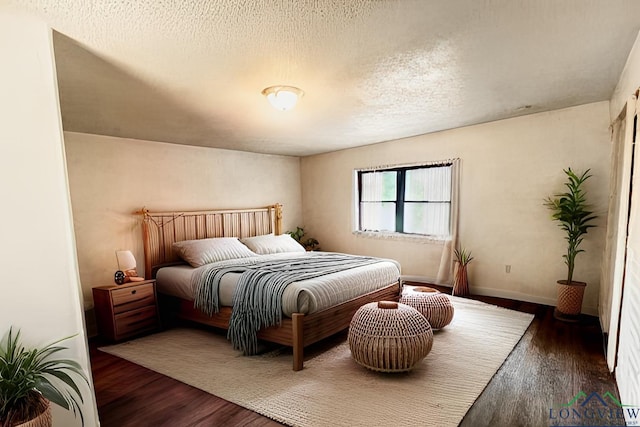 bedroom with a textured ceiling and dark wood-type flooring