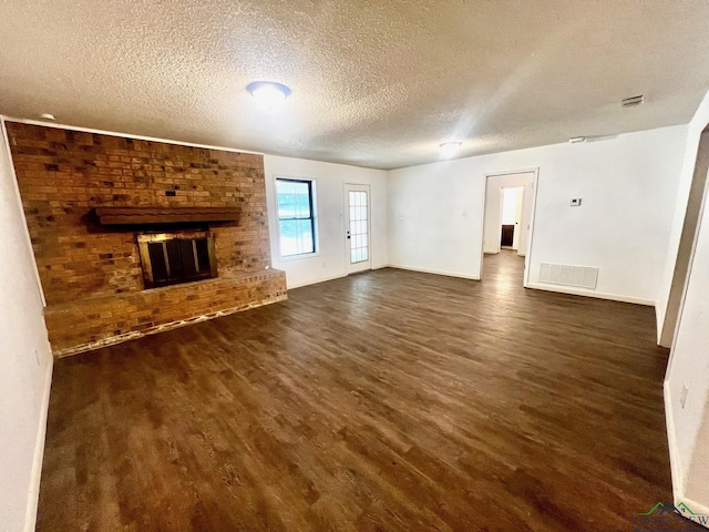 unfurnished living room featuring dark hardwood / wood-style flooring, a textured ceiling, and a brick fireplace