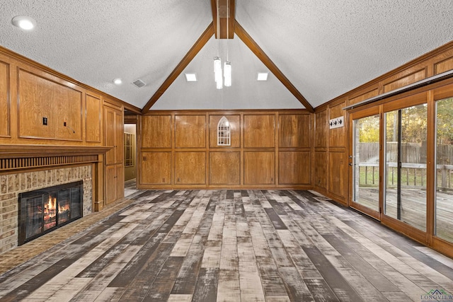 5 Amy Scott Ct, Longview, TX 75605 - unfurnished living room featuring dark wood-style flooring, a textured ceiling, a decorative wall, a fireplace, and wood walls