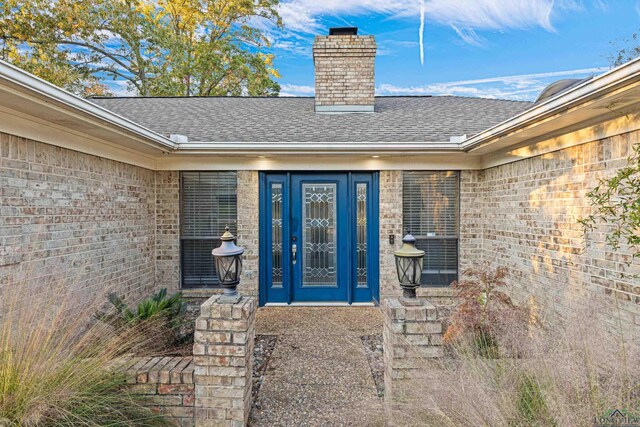 5 Amy Scott Ct, Longview, TX 75605 - property entrance featuring a shingled roof, brick siding, and a chimney