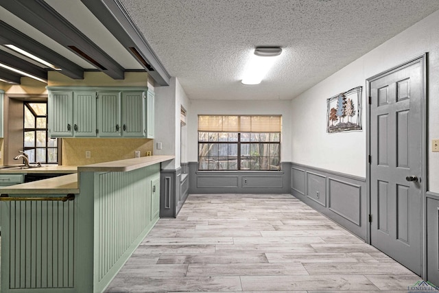 5 Amy Scott Ct, Longview, TX 75605 - kitchen featuring green cabinets, wainscoting, light wood-type flooring, a textured ceiling, and light countertops