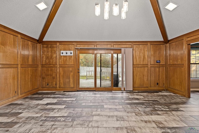 5 Amy Scott Ct, Longview, TX 75605 - unfurnished living room featuring beam ceiling, high vaulted ceiling, wood walls, and wood finished floors