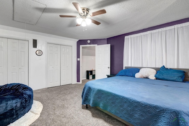 bedroom with ceiling fan, carpet floors, a textured ceiling, and multiple closets