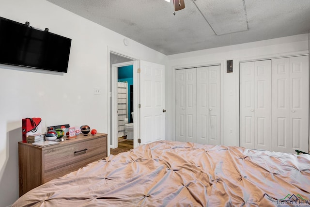 bedroom featuring ceiling fan, a textured ceiling, and two closets