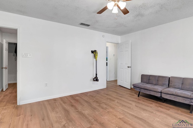 unfurnished living room with light wood-type flooring, a textured ceiling, and ceiling fan