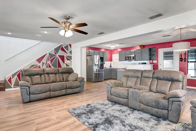 living room with a textured ceiling, light hardwood / wood-style flooring, and ceiling fan