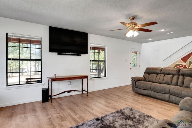 living room featuring a textured ceiling, light hardwood / wood-style floors, a wealth of natural light, and ceiling fan