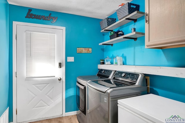 washroom with washing machine and clothes dryer, cabinets, a textured ceiling, and light wood-type flooring