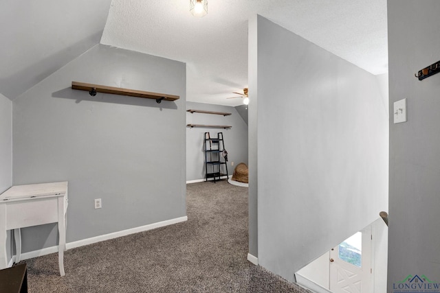 corridor featuring carpet flooring, a textured ceiling, and vaulted ceiling