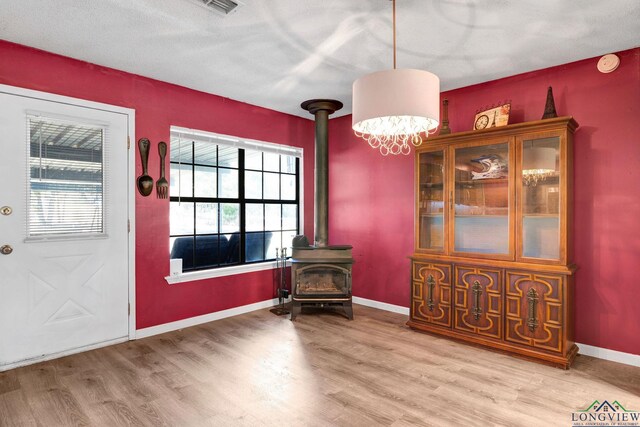 dining room with hardwood / wood-style flooring, a wood stove, and a textured ceiling