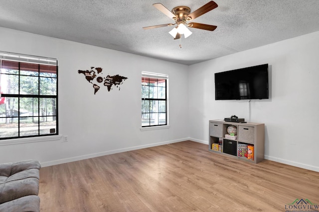 living room with light wood-type flooring, a textured ceiling, and ceiling fan