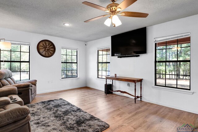 living room with ceiling fan, plenty of natural light, a textured ceiling, and light hardwood / wood-style flooring