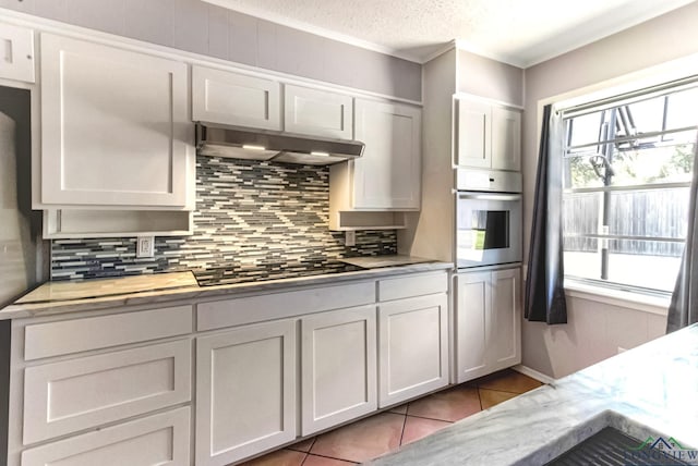 2104 Mccann Rd, Longview, TX 75601 - kitchen featuring appliances with stainless steel finishes, under cabinet range hood, backsplash, crown molding, and tile patterned floors