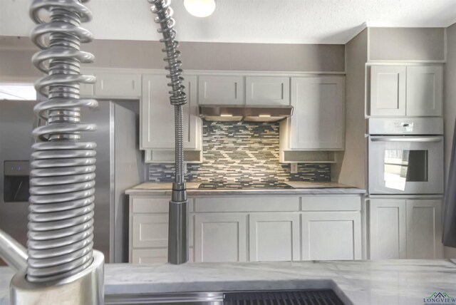 2104 Mccann Rd, Longview, TX 75601 - kitchen with appliances with stainless steel finishes, decorative backsplash, light stone counters, and under cabinet range hood