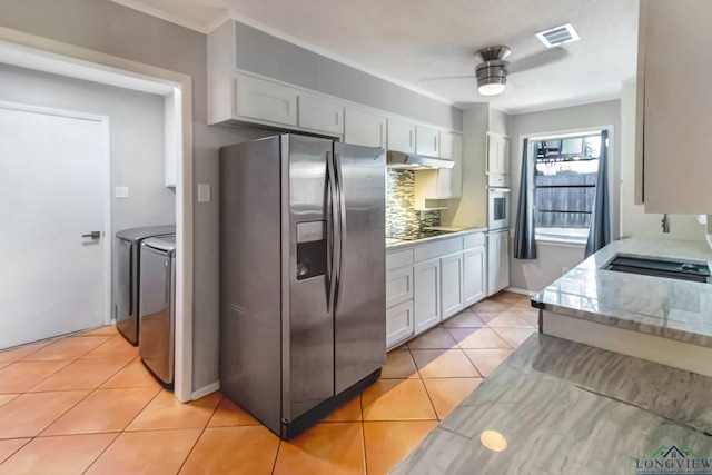 2104 Mccann Rd, Longview, TX 75601 - kitchen featuring stainless steel appliances, independent washer and dryer, under cabinet range hood, light tile patterned flooring, and a ceiling fan