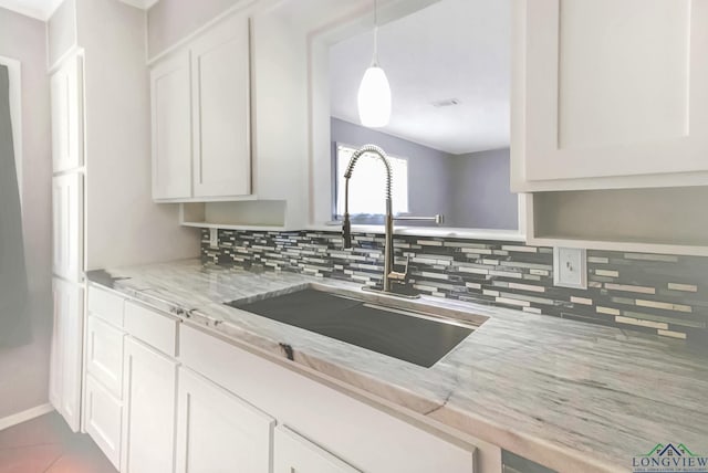 2104 Mccann Rd, Longview, TX 75601 - kitchen featuring backsplash, light stone countertops, white cabinetry, and pendant lighting