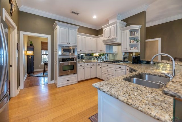 kitchen featuring sink, appliances with stainless steel finishes, white cabinetry, light stone counters, and light wood-type flooring