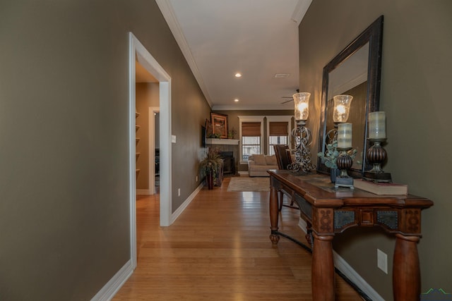 hallway with crown molding, built in features, and light hardwood / wood-style flooring