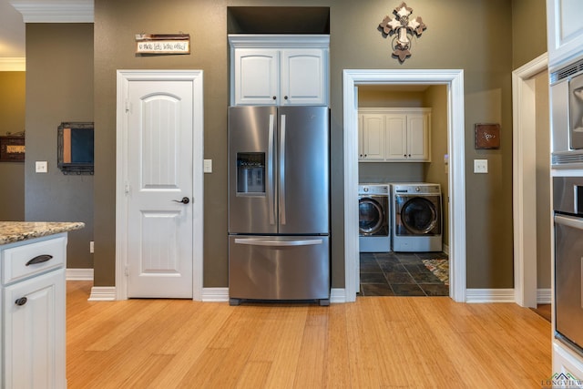 kitchen featuring white cabinetry, stainless steel refrigerator with ice dispenser, washing machine and clothes dryer, and light hardwood / wood-style flooring