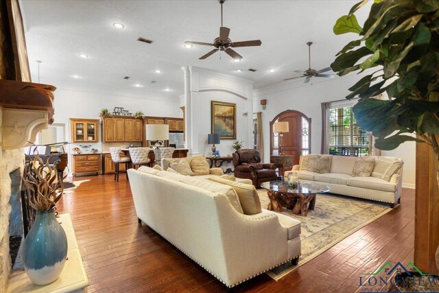 909 University Dr, Carthage, TX 75633 - living area featuring a ceiling fan, ornamental molding, arched walkways, dark wood finished floors, and a fireplace