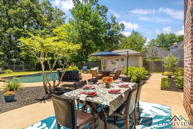 909 University Dr, Carthage, TX 75633 - fenced backyard featuring outdoor dining area, a patio area, and view of scattered trees
